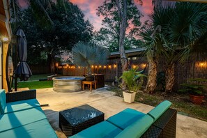 An outdoor patio with seating, a hot tub, and string lights.