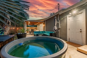 Un patio trasero con un jacuzzi, una terraza de madera y un área de patio con mobiliario exterior.