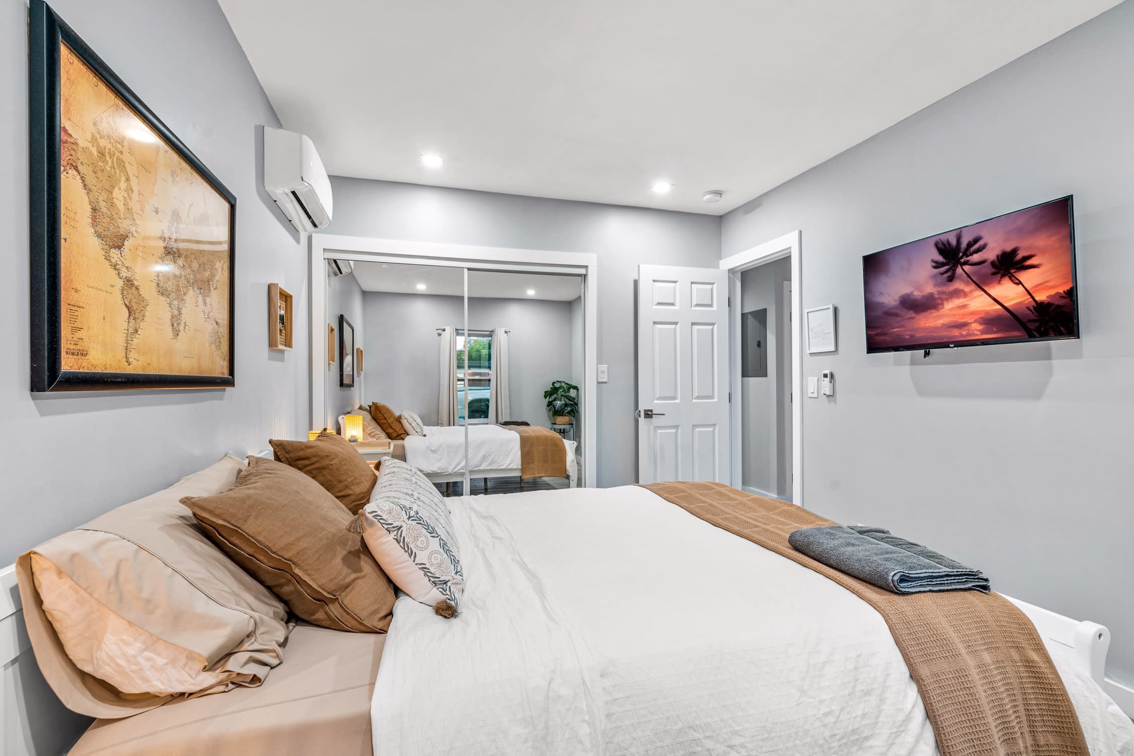 Een moderne hotelkamer met een groot bed, een televisie en een wereldkaart aan de muur.