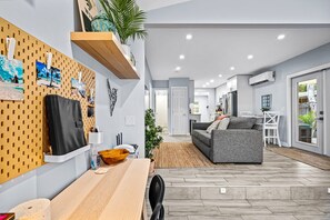 Una sala de estar moderna con un sofá gris, una mesa de centro de madera y un panel de corcho con fotos.