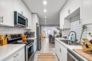 A modern kitchen with white cabinets, stainless steel appliances, and a central island.