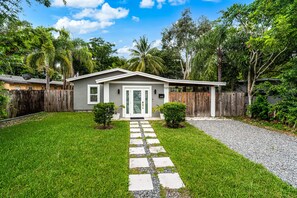 A single-story house with a front yard, a gravel driveway, and a wooden fence.