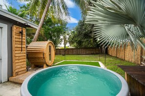 Een achtertuin met een zwembad, een sauna en een houten terras.