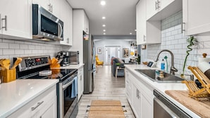 A modern kitchen with white cabinets, stainless steel appliances, and a central island. - Zen Retreat - Sauna, Pool, Cold Plunge & More! (Fort Lauderdale)