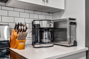 A kitchen with a coffee maker, a toaster, and a knife block on the counter.
