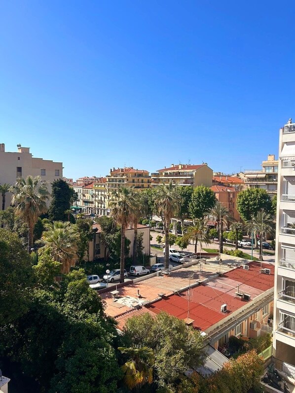 A residential area with multi-story buildings, palm trees, and a red-roofed plaza.