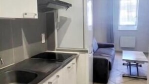 Une cuisine compacte avec des meubles blancs, un plan de travail noir et un four encastré.