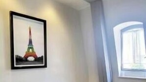 Un salon moderne avec un canapé gris, une table basse blanche et un tableau encadré représentant la Tour Eiffel.