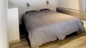Une petite chambre mansardée avec un plafond en pente, un lit simple et un plancher en bois.
