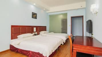 A hotel room with a large bed, a wooden desk, and a television.