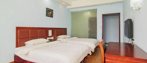 A hotel room with a large bed, a wooden desk, and a television.