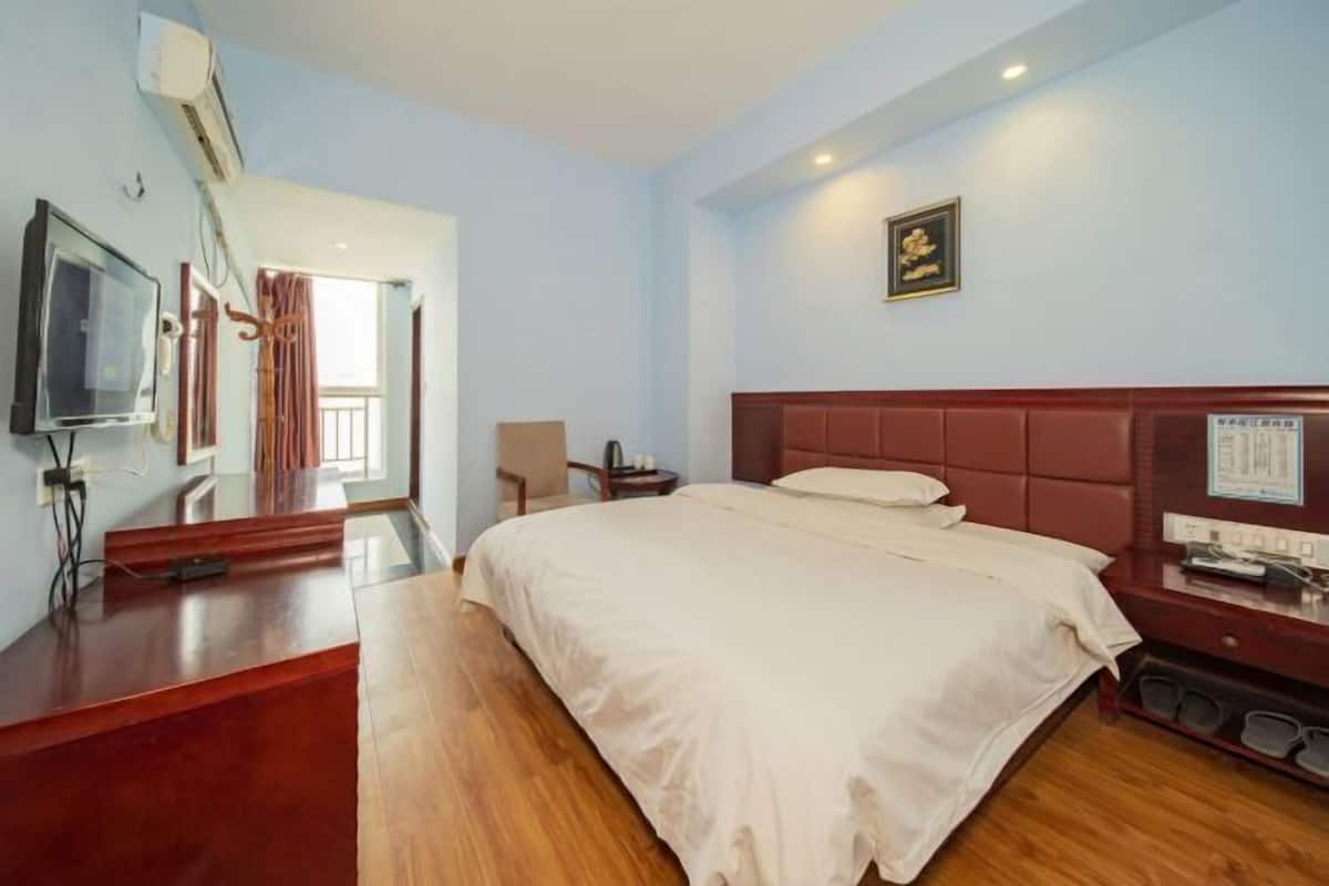 A hotel room with a bed, a desk, a chair, a television, and a window.