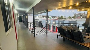 A corridor with a bench area, a staircase, and a view of buildings in the distance. - Chayo's Departamentos (Ensenada)