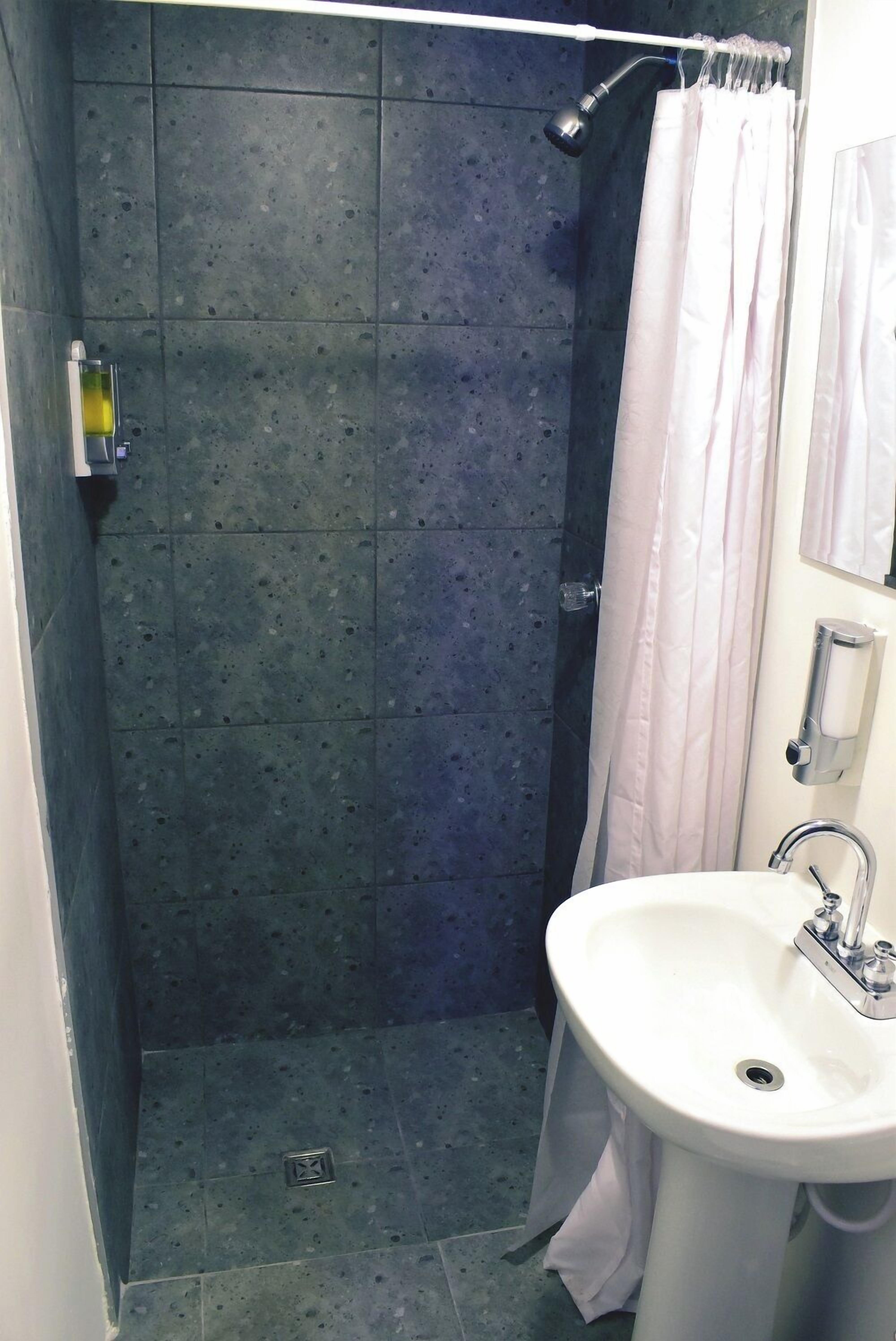 A bathroom with a shower, a sink, and a mirror.