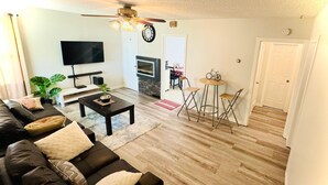 A living room with a sofa, coffee table, TV, fireplace, and a dining area with chairs and a table. - Beautiful house//self check in//7 mins to YEG Airport//Nature walk🌴 (Leduc)
