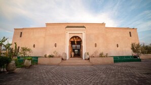 A building with a symmetrical facade, a central entrance with an archway, and a paved courtyard. - Al Destino Luxury Villa & Spa Marrakech (Oulad Hassoune)