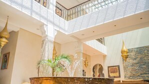 A luxurious indoor fountain with water jets, surrounded by a high ceiling with intricate railings and a stone wall. - Al Destino Luxury Villa & Spa Marrakech (Oulad Hassoune)