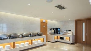 Una habitación de hotel moderna con un espacio tipo buffet, un televisor y una puerta de madera.