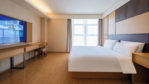 Una habitación de hotel moderna con una cama grande, un escritorio y una televisión.