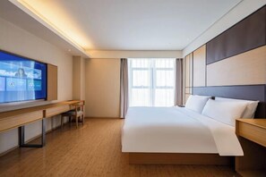 Una habitación de hotel moderna con una cama grande, un escritorio y una televisión.