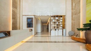 Un moderno vestíbulo de hotel con piso de mármol, una recepción, una escalera y una estantería.