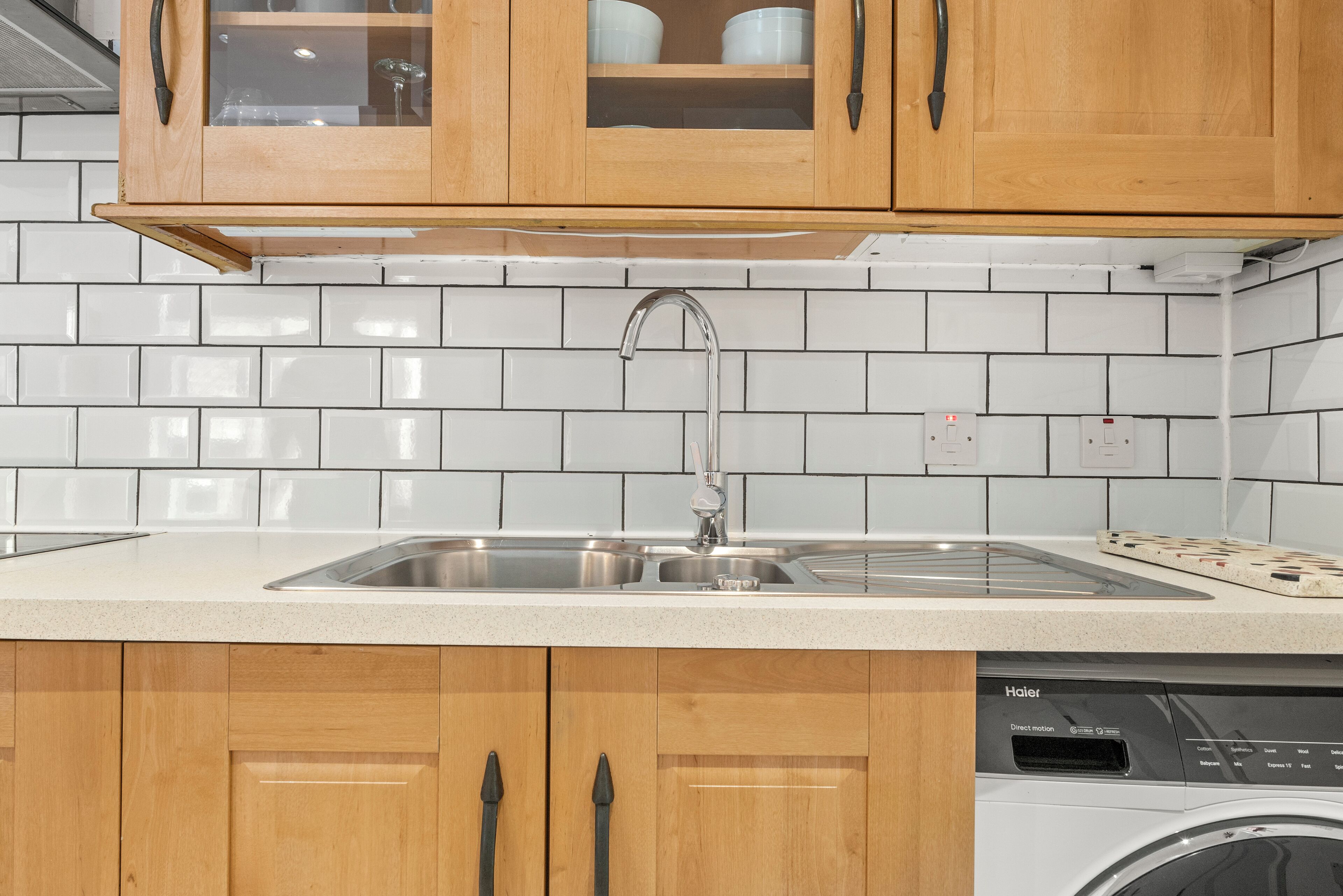 A kitchen with wooden cabinets, a stainless steel sink, and a dishwasher.