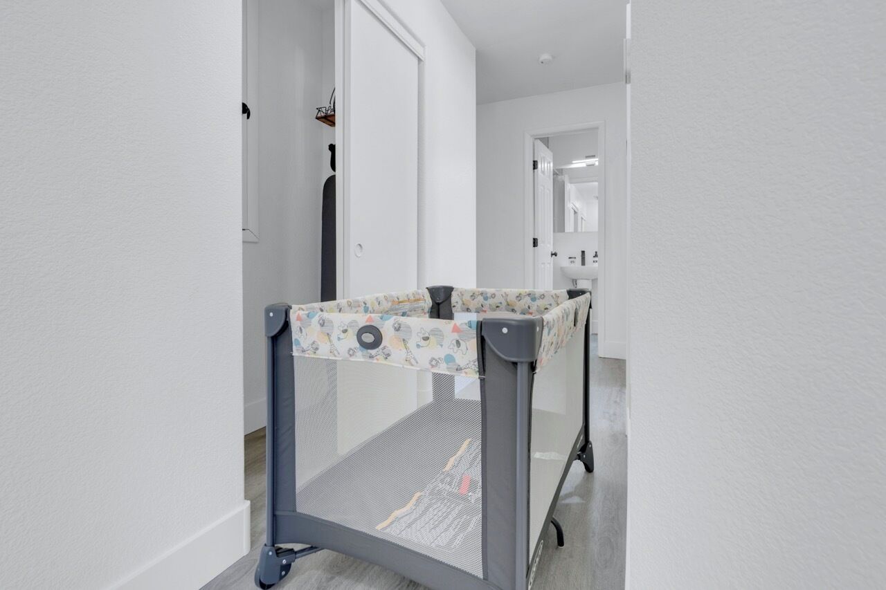 A baby playpen in a hallway with white walls and a door in the background.