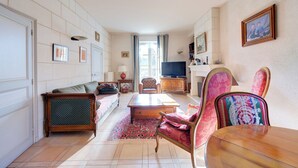 Un salon spacieux comprenant un canapé, des fauteuils, une table basse et un téléviseur.