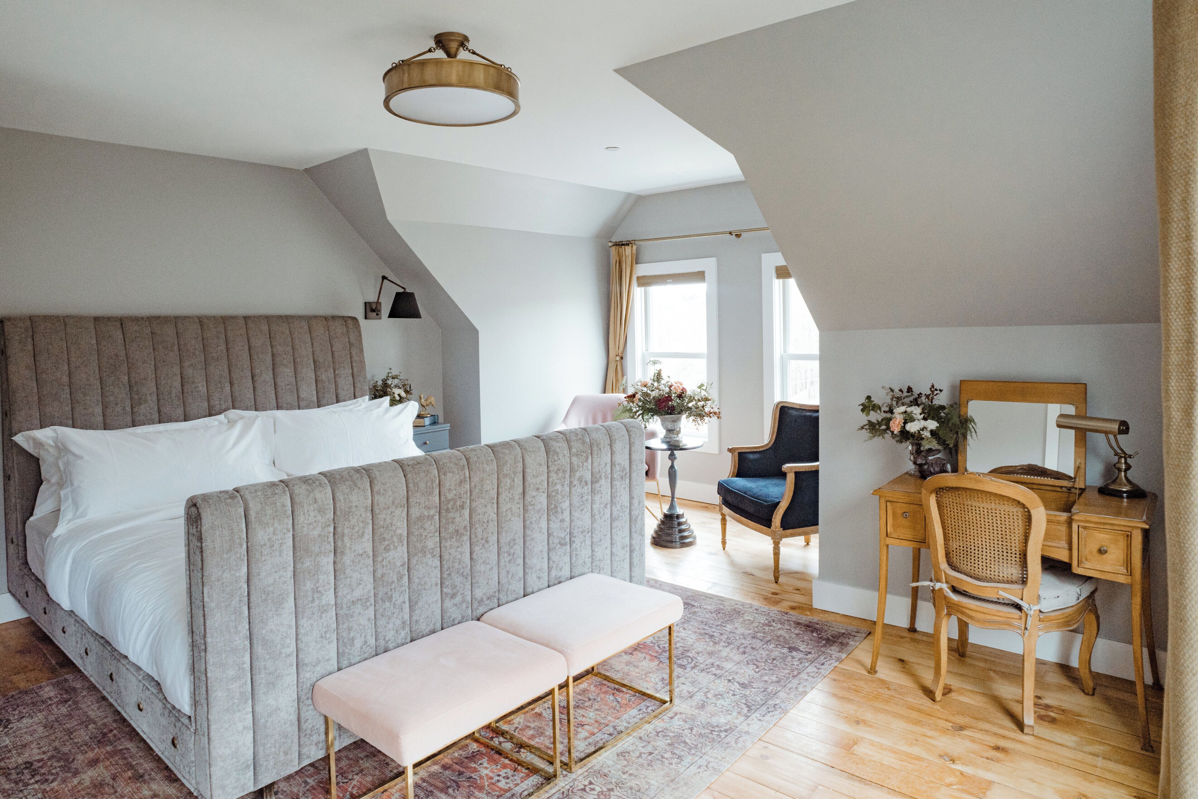 A bedroom with a large bed, a bench, a desk, and a chair.