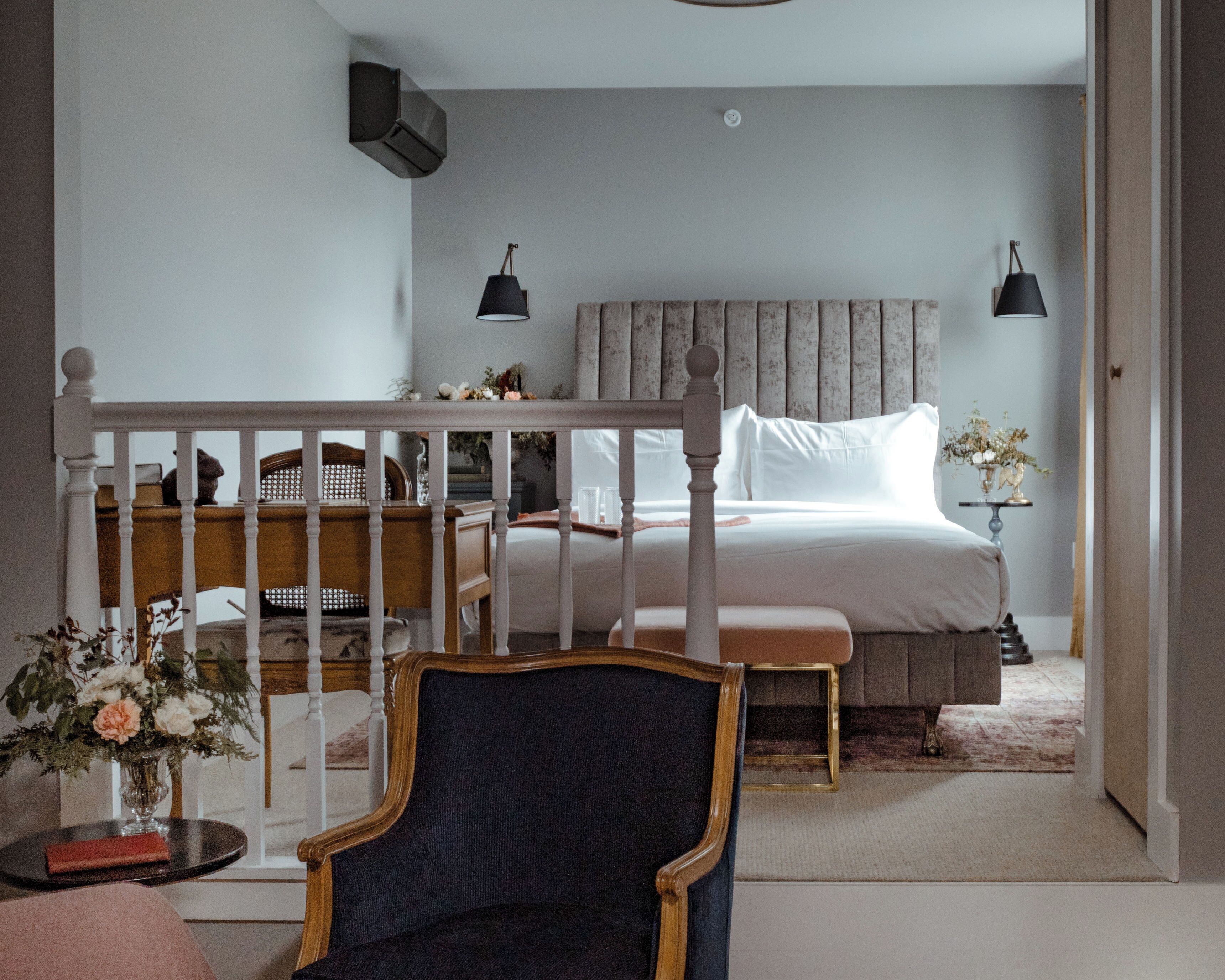 A bedroom with a bed, a chair, a nightstand, and a lamp.