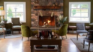 Una sala de estar con chimenea de piedra, dos sillones, una mesa de centro y una estantería.