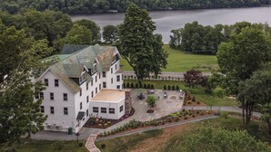 Una casa grande de color blanco con techo verde, rodeada por un césped cuidado y vistas a un lago.