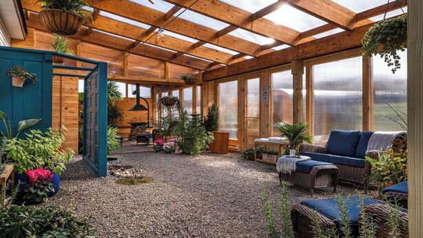 Un solárium con vigas de madera, ventanas amplias y una variedad de plantas en macetas.
