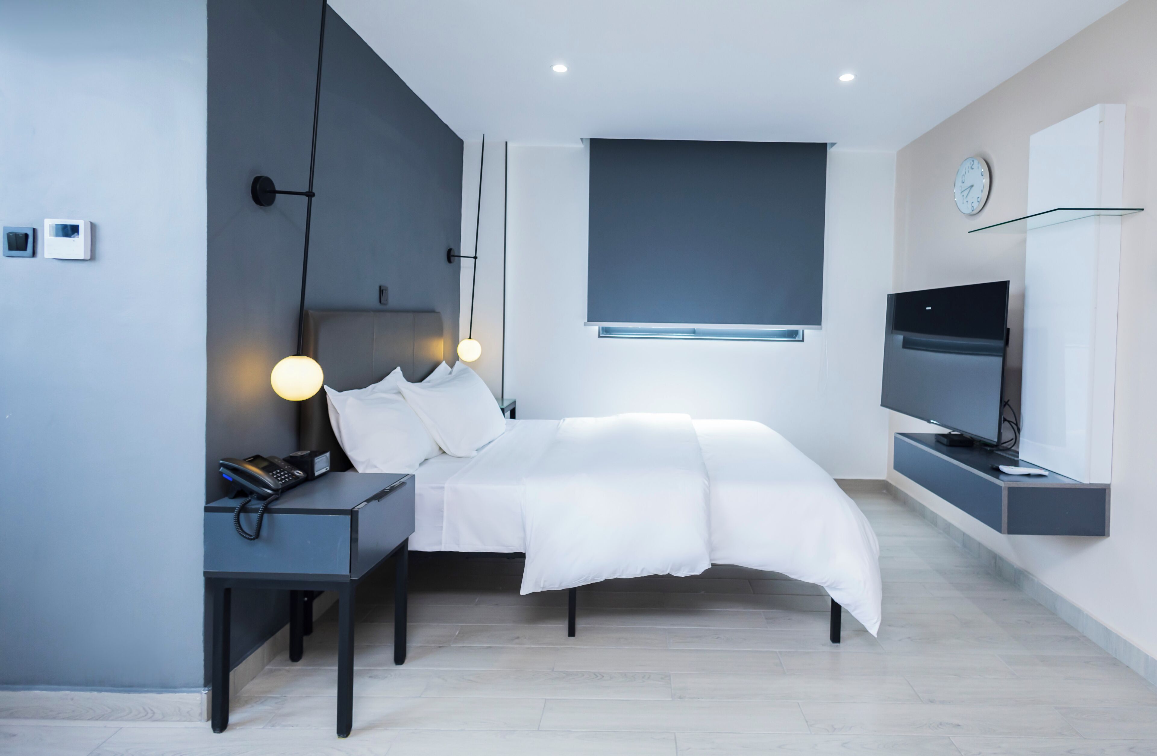A modern bedroom with a bed, bedside table, lamp, and a mounted TV.