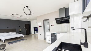 A modern hotel room with a bed, a desk, a kitchenette, and a bathroom. - Bankable Roomzzz (Accra)