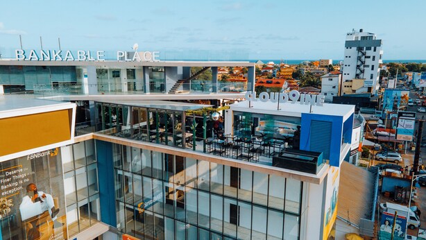 A modern building with a glass facade, a rooftop bar, and signage for 'BANKABLE PLACE' and 'CLOUD9'. - Bankable Roomzzz (Accra)