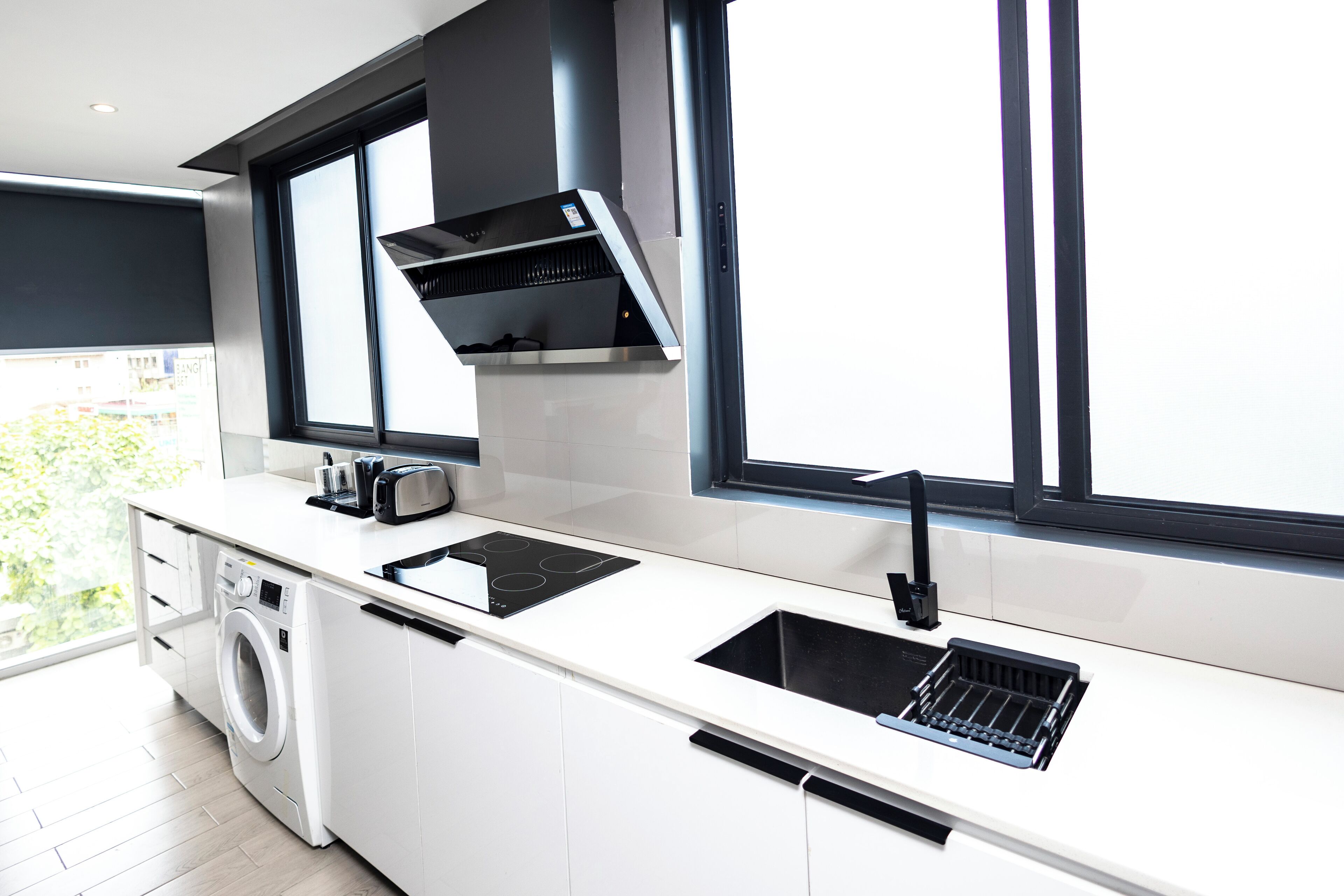 A modern kitchen with a built-in washer, a sink, and a window overlooking a cityscape.