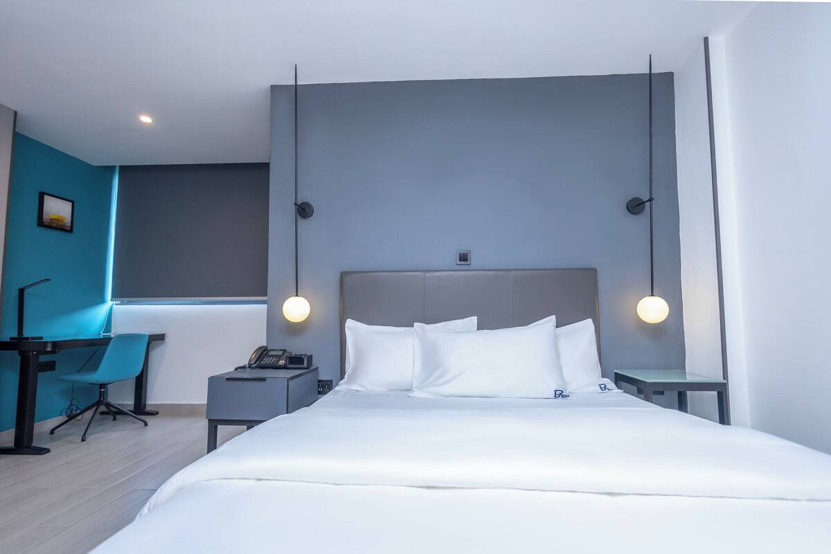 A modern hotel room with a large bed, a desk, and a chair.
