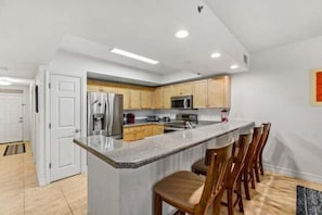 Une cuisine moderne avec un îlot central, des chaises en bois et une porte blanche.