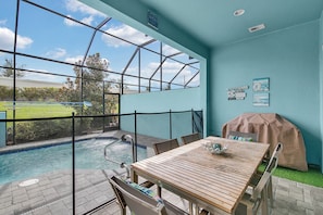 A poolside area with a wooden table, chairs, and a barbecue grill. - 4 BD/ 3.5 BA/ The Enclaves at Festival (382 CD) (Davenport)