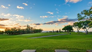 A golf course with a clear sky, trees, and a view of the ocean. - NEW! Big Island Stay with Private Lanai, Golf Course, Pool, Pickleball, & Views! (Waikoloa Village)