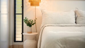 A bedroom with a bed, a bedside lamp, a window, and a wall-mounted painting. - NEW! Big Island Stay with Private Lanai, Golf Course, Pool, Pickleball, & Views! (Waikoloa Village)