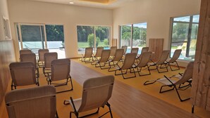 Un salón de conferencias con filas de sillas, ventanas amplias y techo de madera.