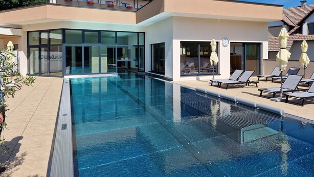 Un hotel moderno con piscina, tumbonas y fachada de vidrio.