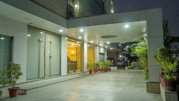 A modern building with a tiled floor, glass doors, and potted plants. - The Horizon Hotel (Ankleshwar)