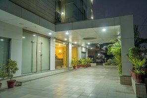 A modern building with a tiled floor, glass doors, and potted plants. - The Horizon Hotel (Ankleshwar)