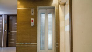 An elevator with a digital display and a door with a grid pattern. - The Horizon Hotel (Ankleshwar)