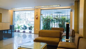 A modern lobby with a glass coffee table, leather sofas, and potted plants. - The Horizon Hotel (Ankleshwar)
