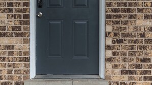 A dark-colored door with the number 311, a metal doorbell, and a doormat with "WELCOME HOME" text. - Gulf - Charming 2Br Lake Front Apartment (Gulfport)