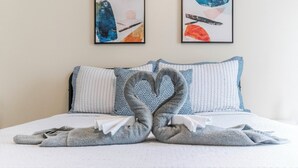 A hotel room with a bed, two pillows, and two abstract paintings on the wall. - Gulf - Charming 2Br Lake Front Apartment (Gulfport)